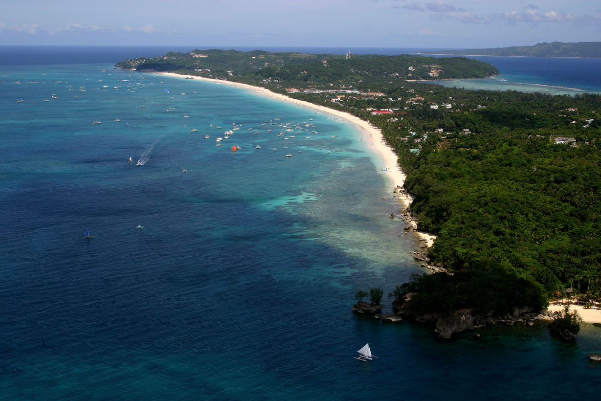 Tranquil body of water surrounded by lush vegetation with several boats, Boracay Island Philippines